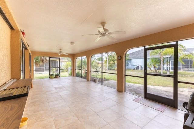 unfurnished sunroom featuring plenty of natural light and a ceiling fan