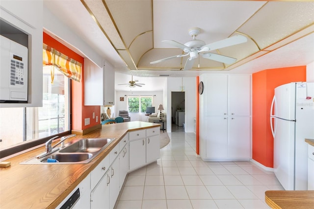 kitchen featuring white appliances, ceiling fan, white cabinetry, a sink, and light tile patterned flooring