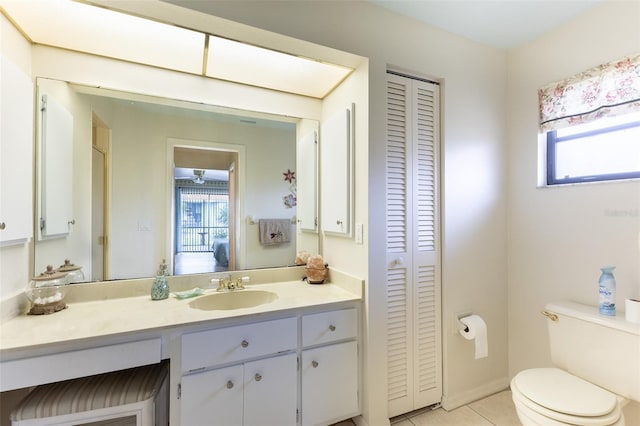 ensuite bathroom with tile patterned flooring, toilet, vanity, a closet, and ensuite bath