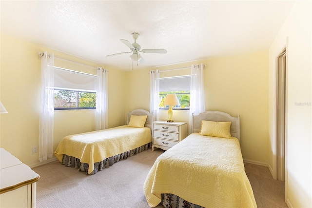 bedroom featuring ceiling fan, multiple windows, baseboards, and carpet flooring