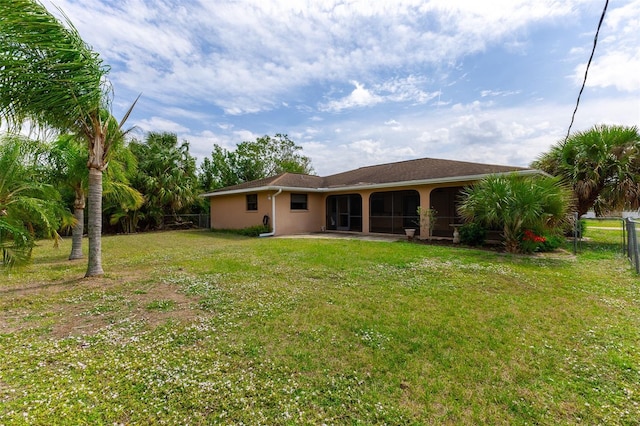 rear view of property featuring a yard, a patio area, fence, and stucco siding