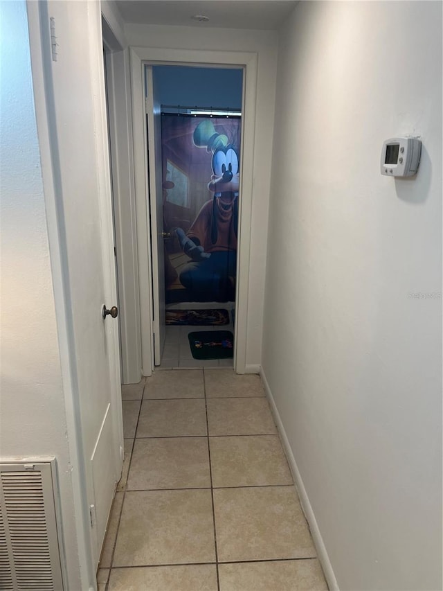 corridor with visible vents, baseboards, and light tile patterned flooring