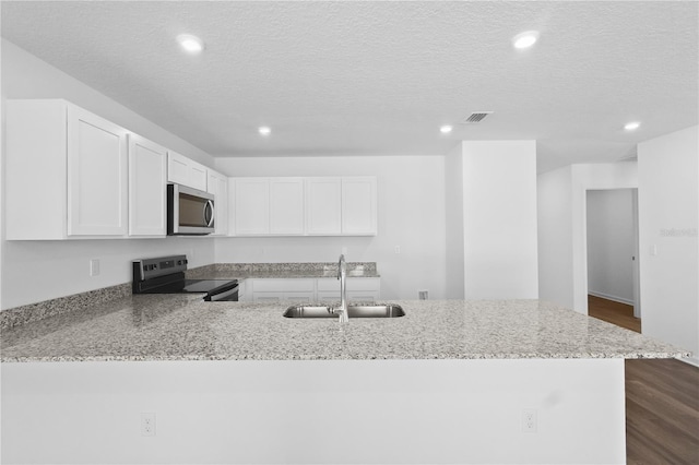 kitchen featuring light stone counters, a peninsula, stainless steel appliances, white cabinetry, and a sink