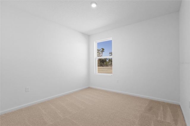 unfurnished room with light colored carpet, a textured ceiling, and baseboards