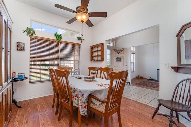 dining room with ceiling fan, light wood-type flooring, a wealth of natural light, and baseboards