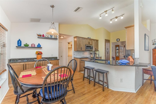 dining room with lofted ceiling, visible vents, light wood-style flooring, and a healthy amount of sunlight