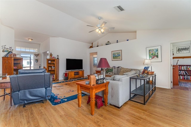 living room featuring vaulted ceiling, light wood-style flooring, visible vents, and a ceiling fan