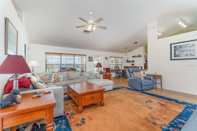 living area with high vaulted ceiling, wood finished floors, visible vents, baseboards, and a ceiling fan