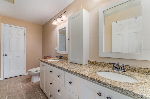 full bathroom featuring toilet, tile patterned flooring, double vanity, and a sink