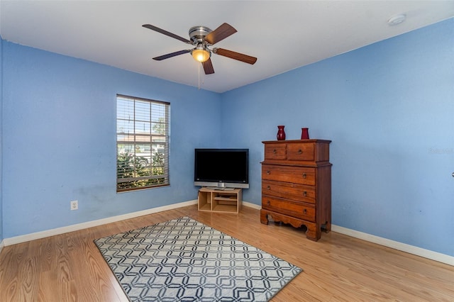 sitting room with a ceiling fan, baseboards, and wood finished floors