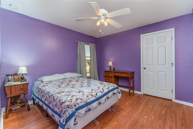 bedroom featuring a ceiling fan, baseboards, and wood finished floors