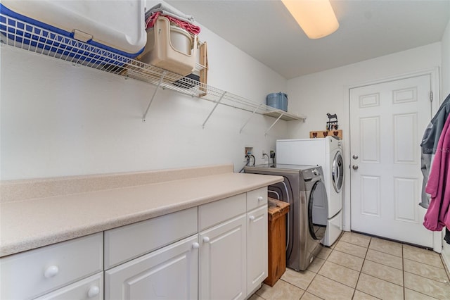 washroom with cabinet space, washing machine and dryer, and light tile patterned floors