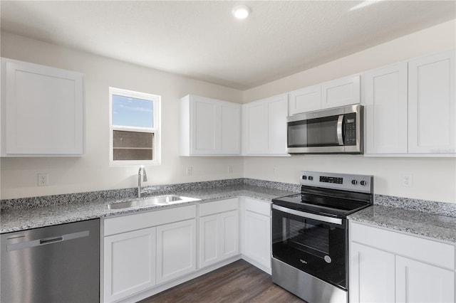 kitchen featuring white cabinets, dark wood-type flooring, stainless steel appliances, and a sink