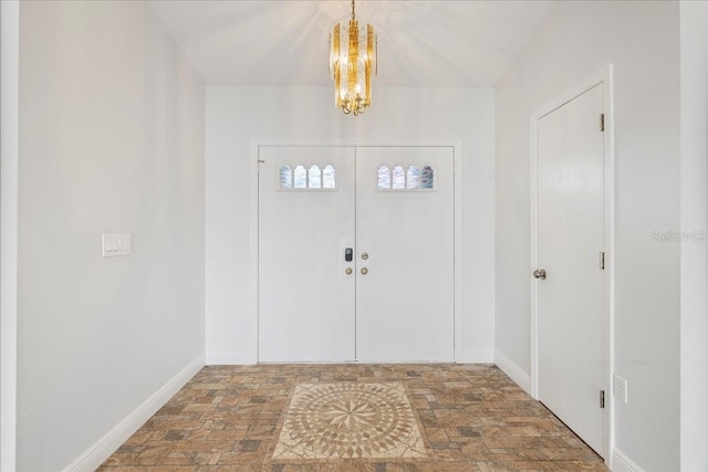 foyer entrance with baseboards and a chandelier