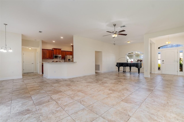 unfurnished living room with baseboards, visible vents, and ceiling fan with notable chandelier