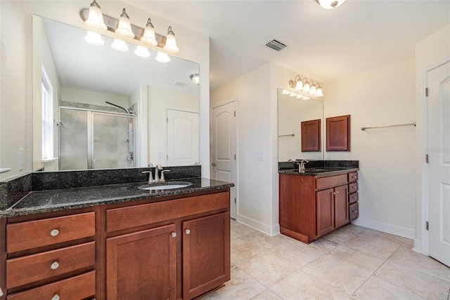 full bathroom featuring a stall shower, baseboards, visible vents, a sink, and two vanities