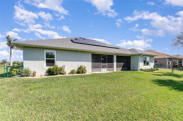 rear view of house with a yard, a fenced backyard, a sunroom, and roof mounted solar panels