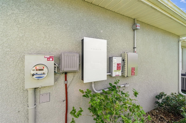 exterior details featuring electric meter and stucco siding