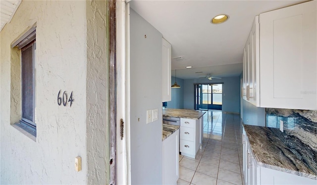 kitchen featuring stone counters, white cabinets, and light tile patterned flooring