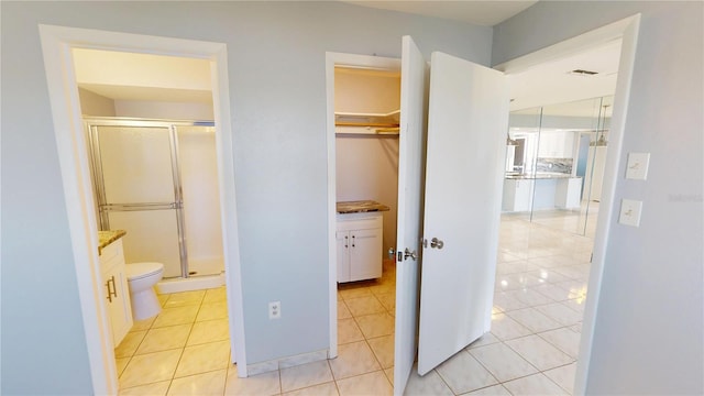 interior space with light tile patterned floors, ensuite bath, and visible vents