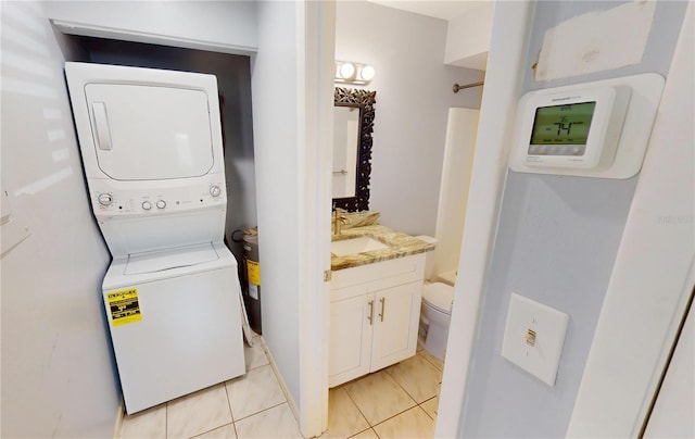 laundry room with laundry area, light tile patterned flooring, a sink, and stacked washer and clothes dryer