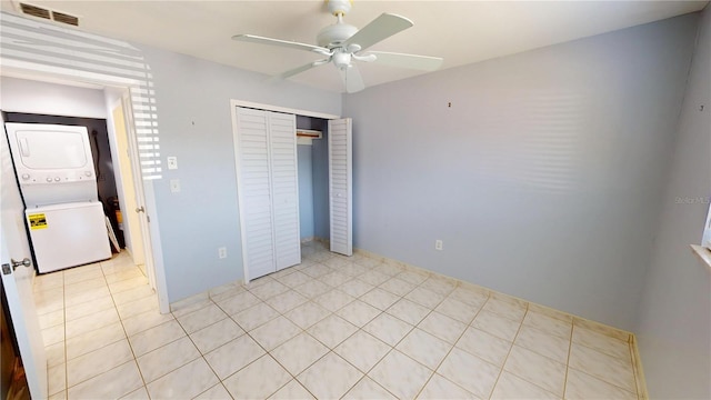 unfurnished bedroom featuring visible vents, ceiling fan, stacked washer / drying machine, a closet, and light tile patterned flooring