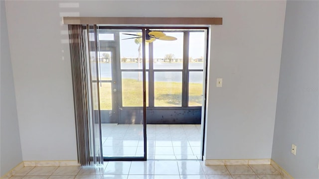 doorway with light tile patterned floors, ceiling fan, and baseboards