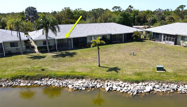 back of house with a water view, a sunroom, and a lawn