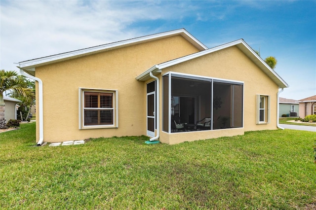 24321 Kintail Ct, Punta Gorda, FL 33980 - rear view of house featuring stucco siding, a sunroom, and a lawn