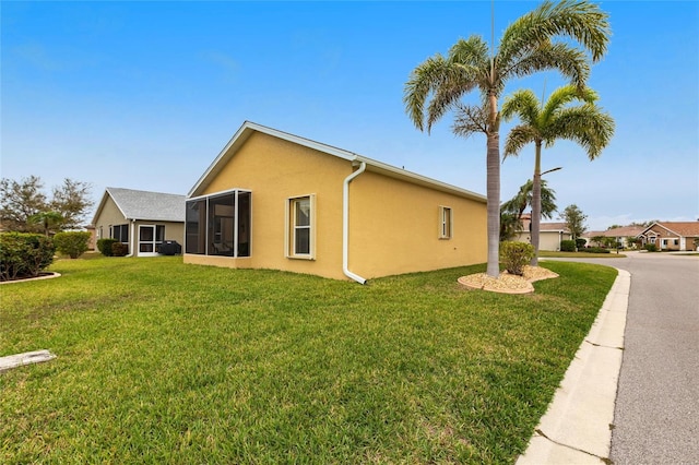 24321 Kintail Ct, Punta Gorda, FL 33980 - view of home's exterior featuring a sunroom, stucco siding, and a lawn