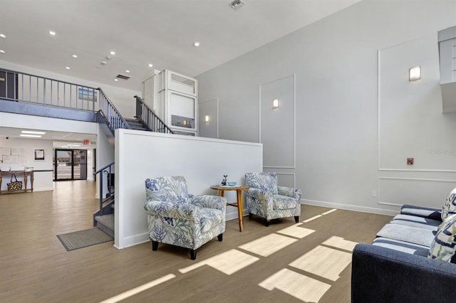 living area featuring visible vents, stairs, recessed lighting, wood finished floors, and a decorative wall