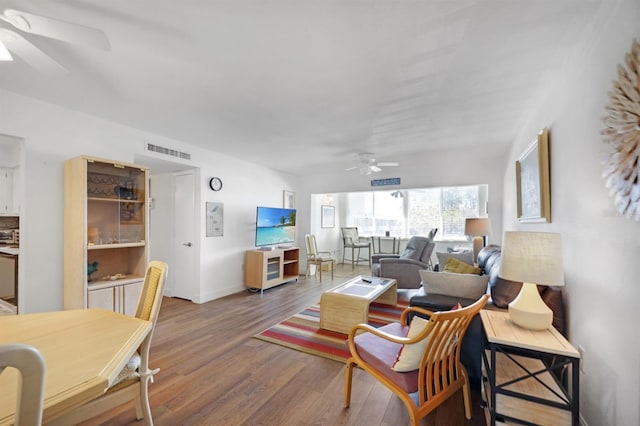 living room featuring wood finished floors, a ceiling fan, visible vents, and baseboards