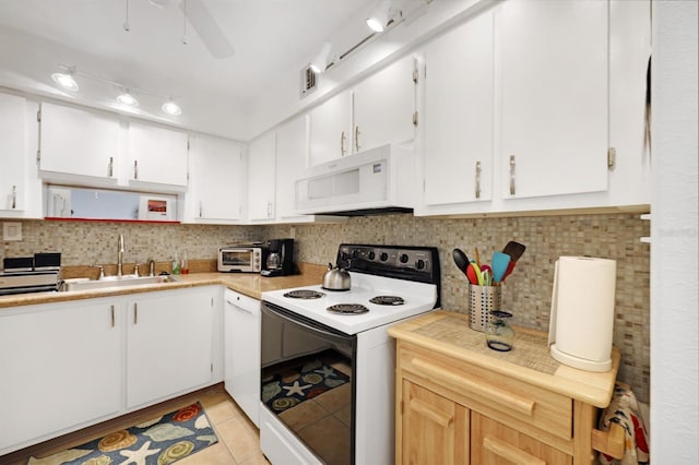 kitchen featuring light tile patterned flooring, decorative backsplash, white appliances, and a sink