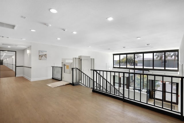 corridor featuring an upstairs landing, visible vents, baseboards, and wood finished floors