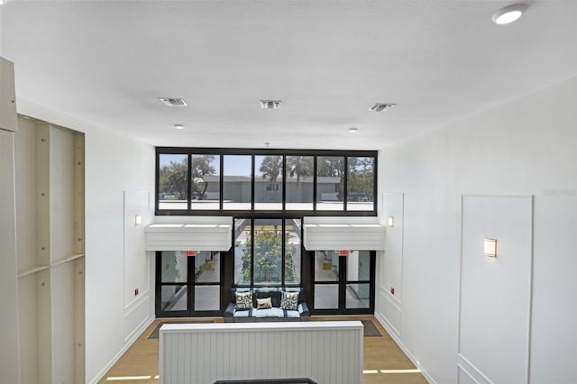 hall featuring visible vents, wood finished floors, and floor to ceiling windows