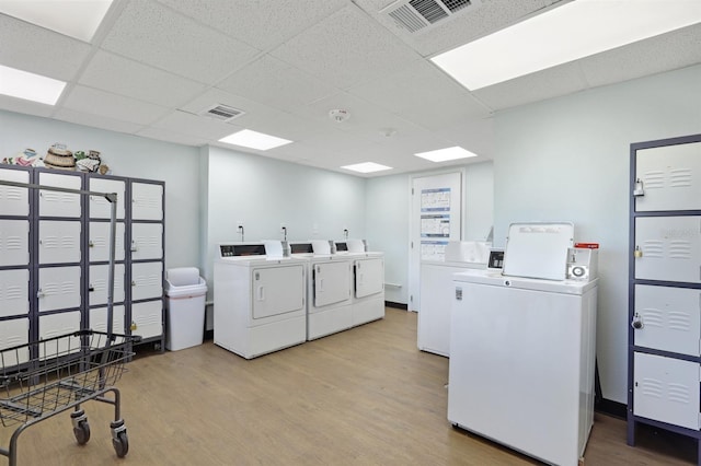 community laundry room with light wood-type flooring, visible vents, and separate washer and dryer