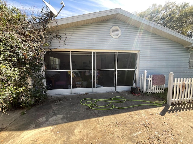 rear view of house with fence and a sunroom