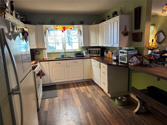 kitchen featuring white appliances, dark wood finished floors, a sink, white cabinetry, and backsplash