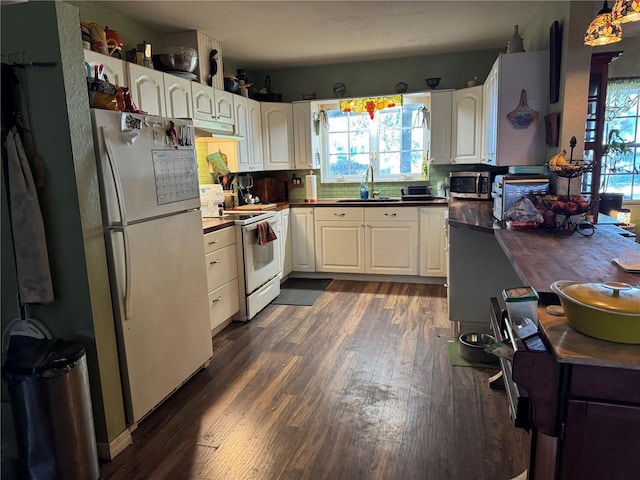 kitchen with dark wood-style floors, decorative backsplash, white cabinets, a sink, and white appliances