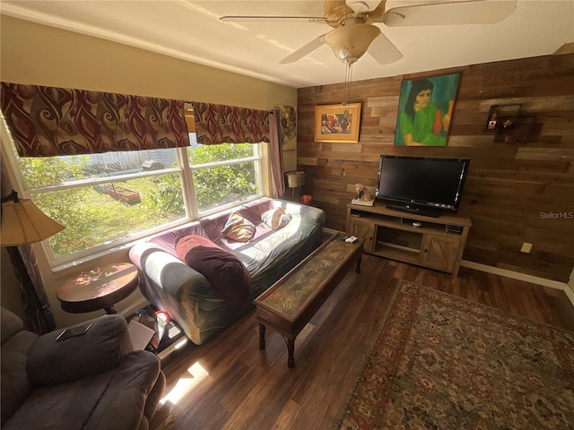 living area featuring wooden walls, a ceiling fan, and dark wood-type flooring