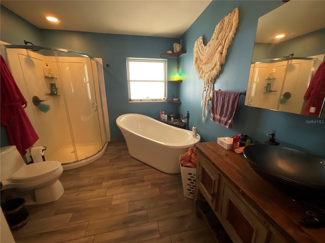 full bath featuring wood finish floors, a freestanding tub, vanity, and a stall shower