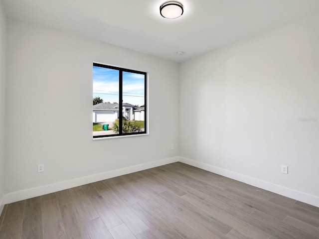 spare room with baseboards and wood finished floors