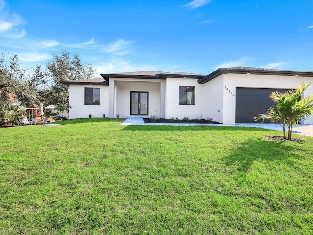 view of front facade with a garage, french doors, a front lawn, and stucco siding