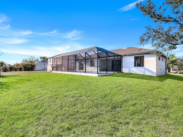 rear view of property featuring a lanai, a lawn, and stucco siding