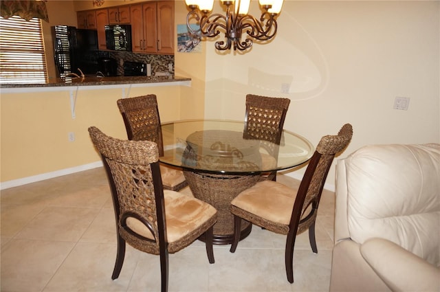 dining room with a chandelier, light tile patterned floors, and baseboards