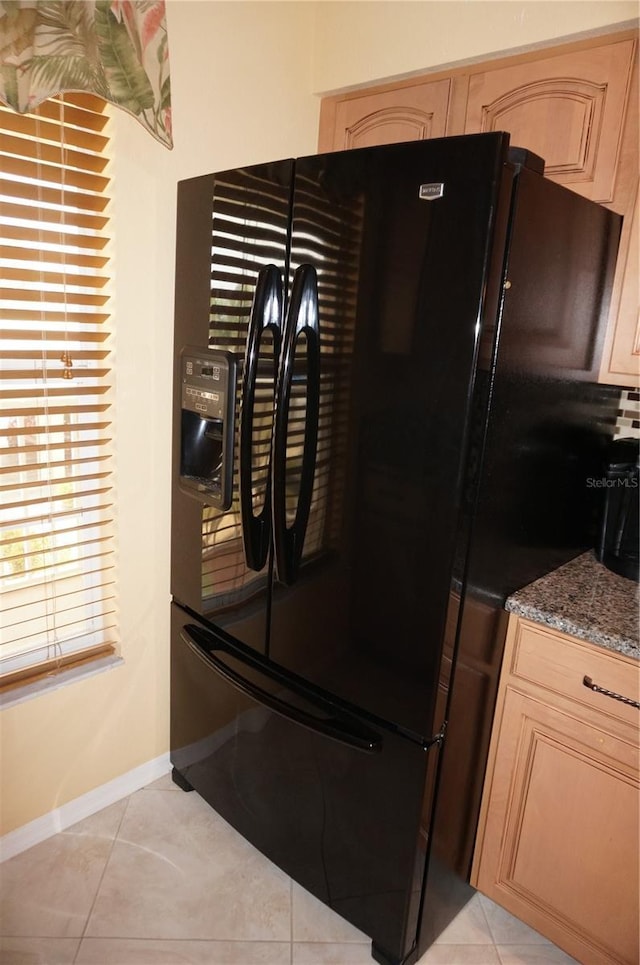 kitchen featuring light tile patterned floors, light brown cabinetry, and freestanding refrigerator