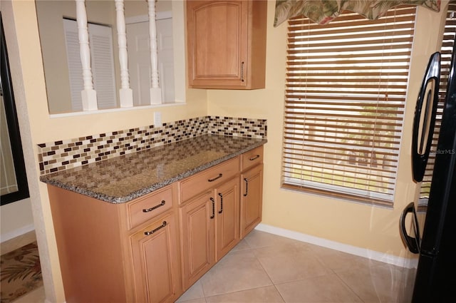 kitchen featuring light tile patterned floors, backsplash, freestanding refrigerator, and baseboards