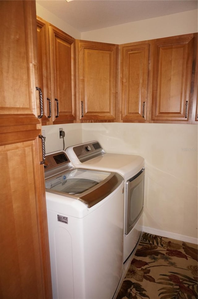 laundry room featuring washer and dryer, cabinet space, and baseboards