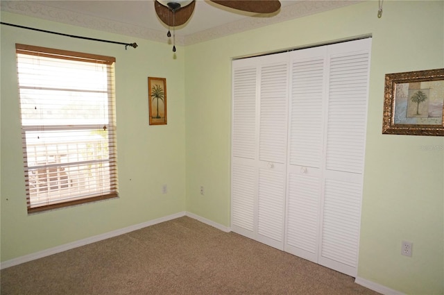 unfurnished bedroom featuring carpet floors, multiple windows, baseboards, and a closet