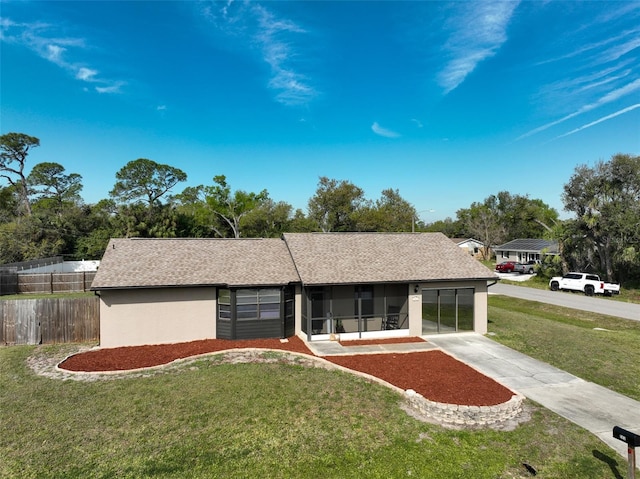 ranch-style home with roof with shingles, stucco siding, a sunroom, fence, and a front lawn